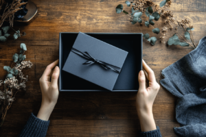 A high-end product unboxing scene on a wooden table, soft natural lighting, premium packaging with elegant textures, hands opening the box, minimalist branding, emotionally engaging atmosphere, cinematic composition